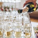 Waiter pouring champagne in stylish glasses at luxury wedding reception