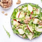 Waldorf salad with red and green apple, green celery, lettuce, arugula and walnuts